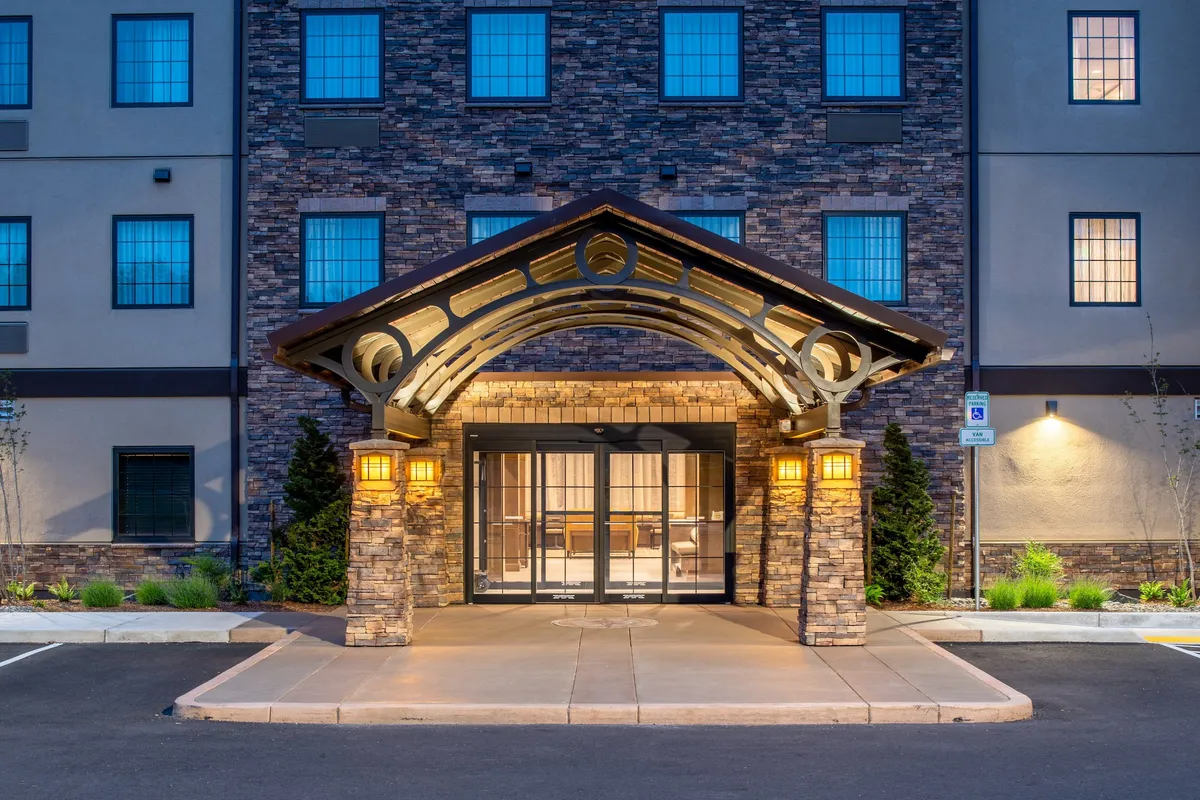 This image features the main entrance of Staybridge Hillsboro North, framed by decorative stonework and large, glowing windows. The well-lit archway creates an inviting entry point, conveying warmth and a welcoming first impression for arriving families, especially in the evening.