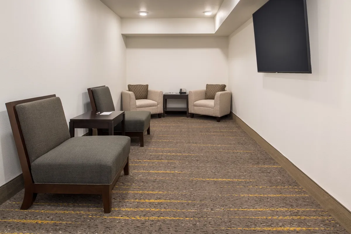 This image displays a comfortable suite seating area with a small table and television, creating a relaxed and inviting atmosphere for guests. The space is designed for both solitude and casual conversation, reflecting the individuality and comfort of each suite.
