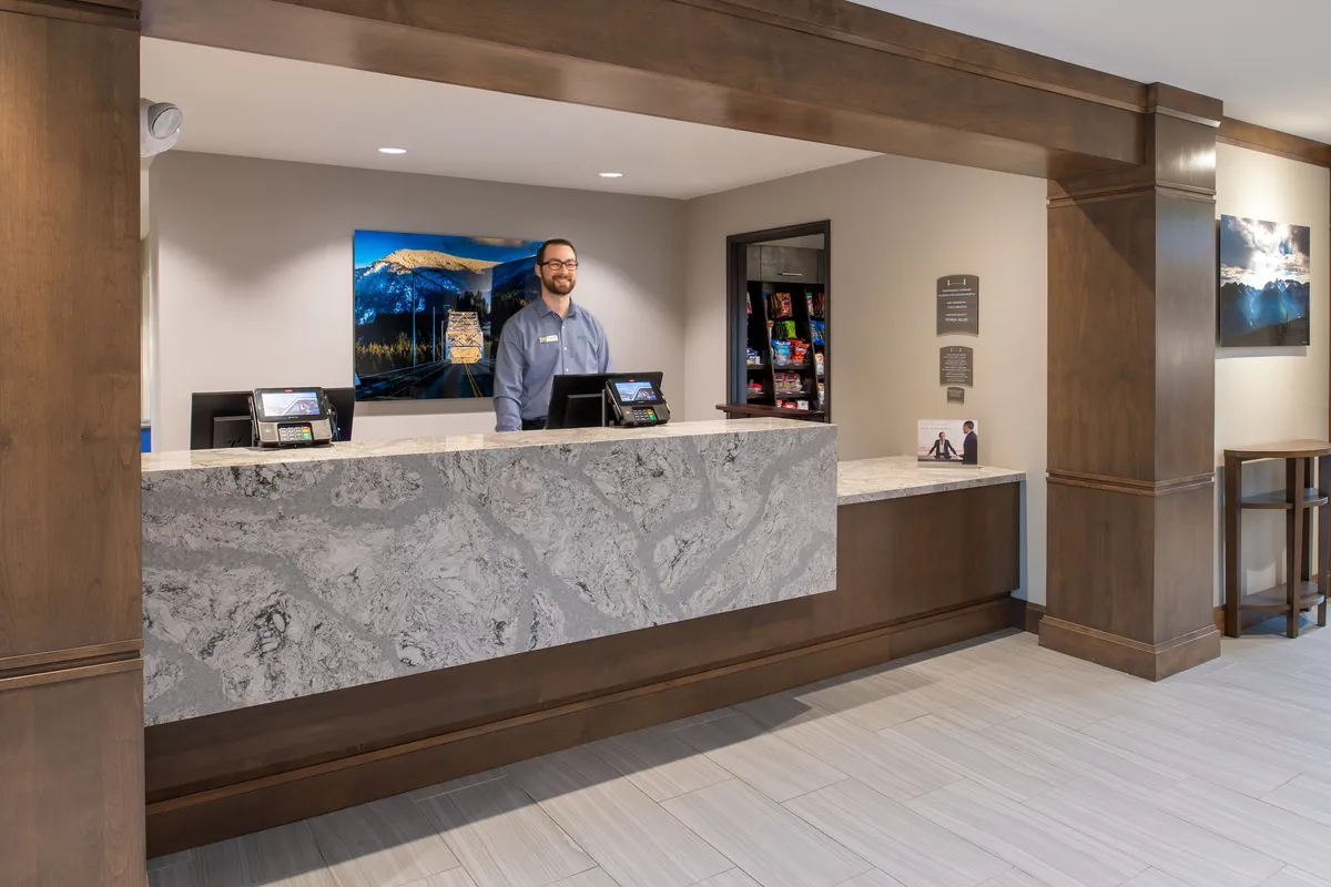 This image shows the hotel's reception area, featuring a friendly staff member behind the desk and eye-catching local artwork on the wall. The atmosphere is welcoming and professional, highlighting the attentive guest services available to visitors.